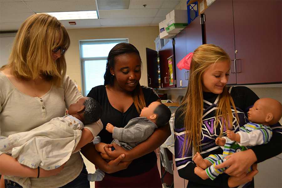 Senior Abby Lanphear, sophomore Cynthia Karanja and junior Mary Kaster play with their baby simulators in class.