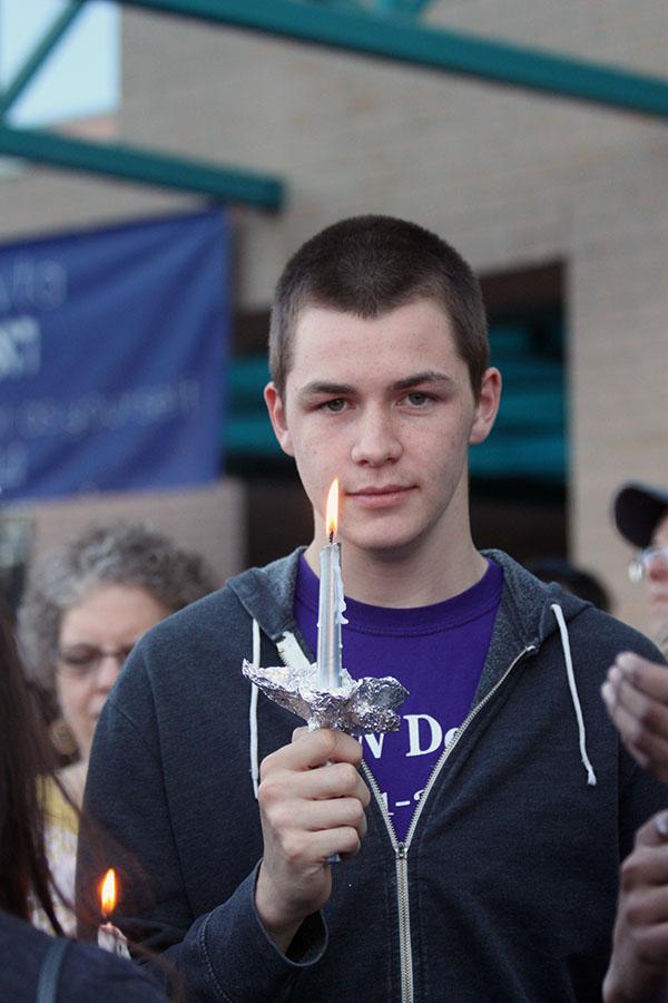 Senior Matt Herndon walks from outside the Jewish Community Center to the start of the walk holding his candle.