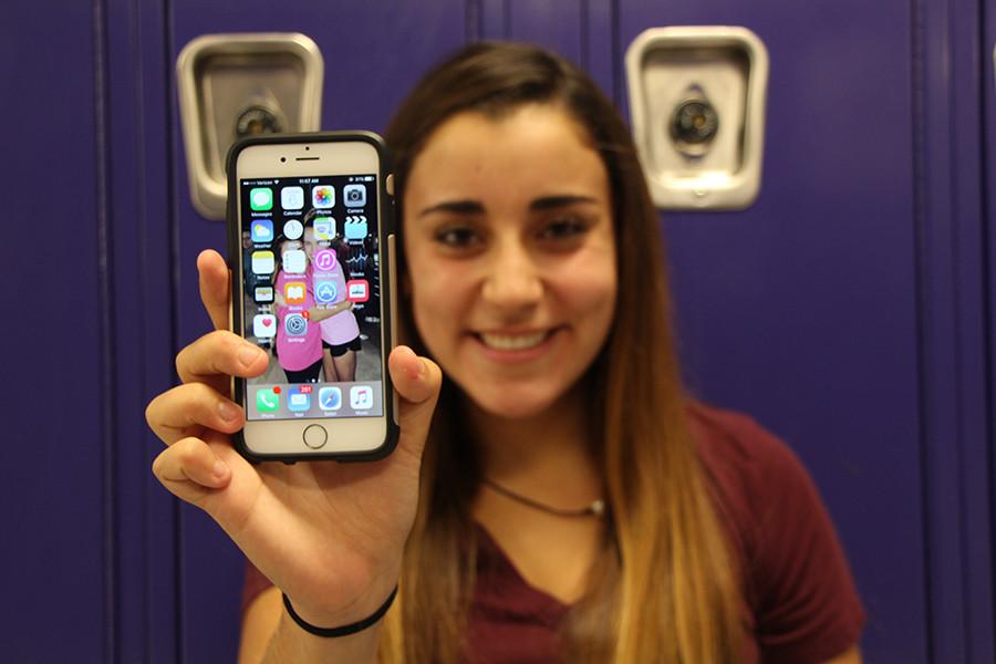 Sophomore Evy Khoury holds up her phone with the iOS 9 update.