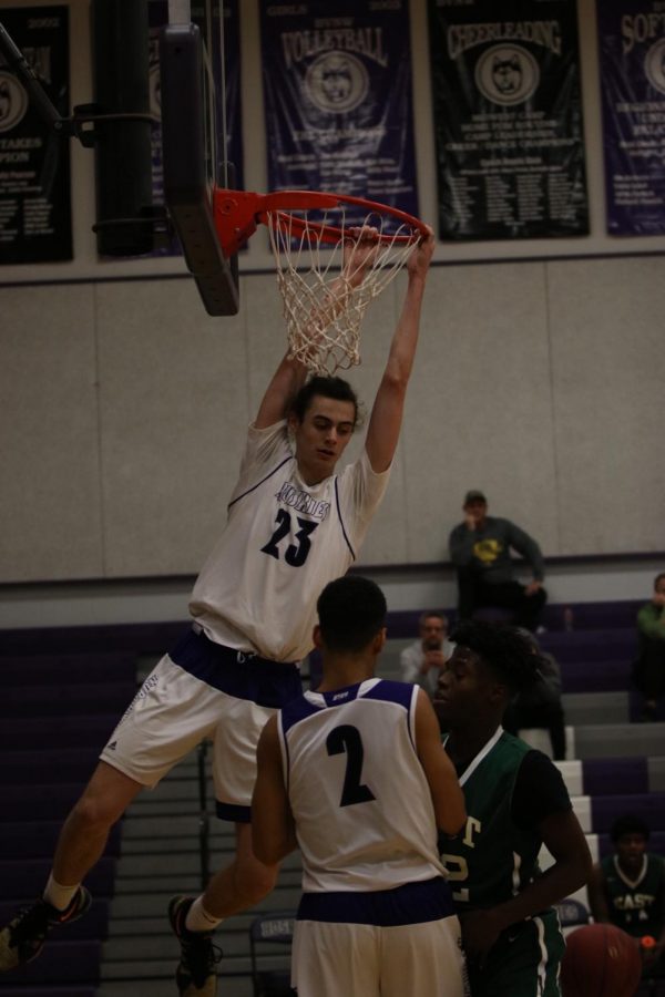 Blue Valley Northwest senior forward Parker Braun (23) hangs on the rim after a dunk during the first half of the Huskies matchup with East at BVNW Jan. 30. The Huskies defeated the Bears, 87-28.