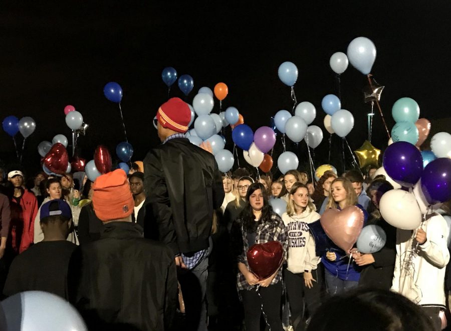 A crowd of people release balloons to honor John Albers.