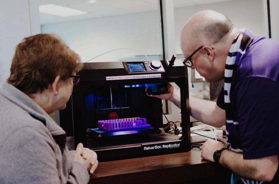 Librarians Mary McCabe and Craig Odle work on fixing the MakerBot.