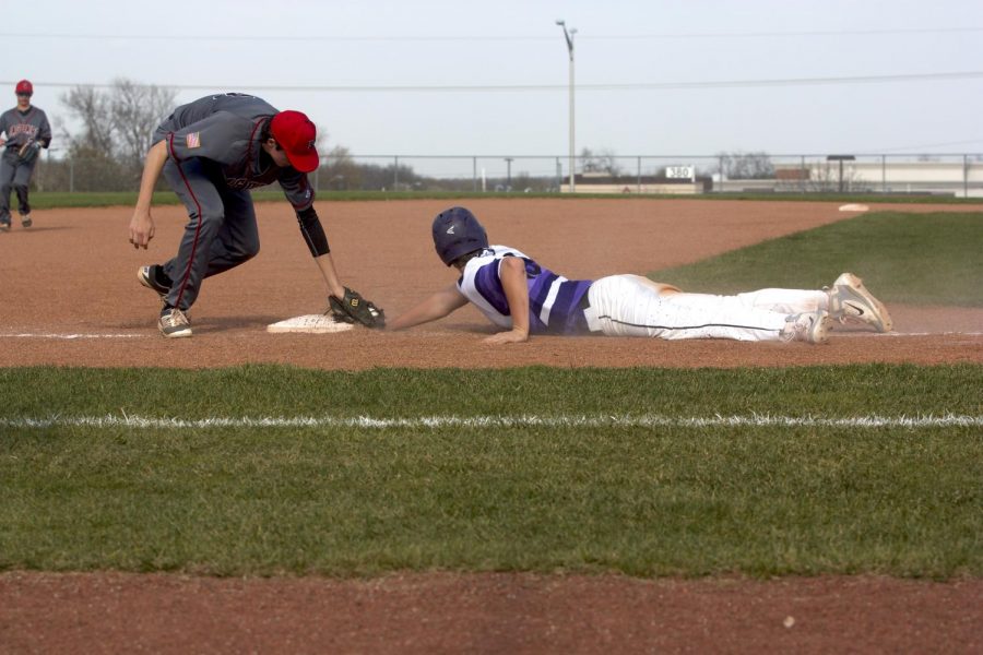 Senior Holden Missey dives back into third base after a Jaguars pickoff attempt in the Huskies matchup with Blue Valley West at the DAC April 24. The Huskies defeated the Jaguars, 10-3.
