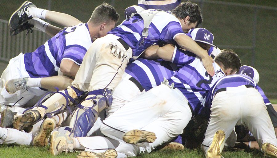 Players of the varsity baseball team dog pile after their game against Olathe East High School at the DAC. The Huskies defeated the Hawks, 2-0. 