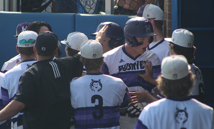 Members of the dugout celebrate with senior first baseman Holden Missey after scoring a run against Derby High School at Hoglund Ballpark May 25. The Huskies defeated the Panthers 4-3.