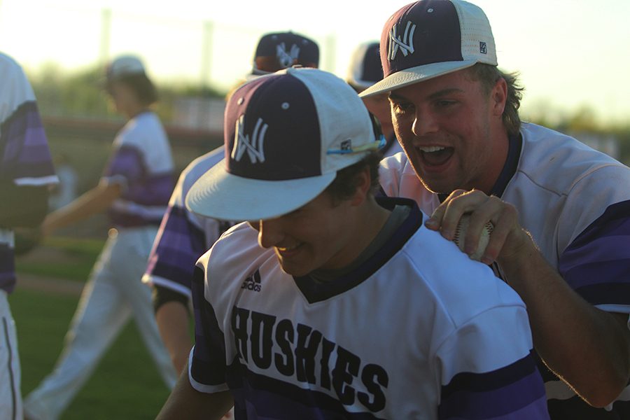 Senior pitcher Will Dennis congratulates junior left fielder Tyler McQuinn after throwing out a Blue Valley North runner at the DAC May 4. The Huskies defeated the Mustangs 5-1.