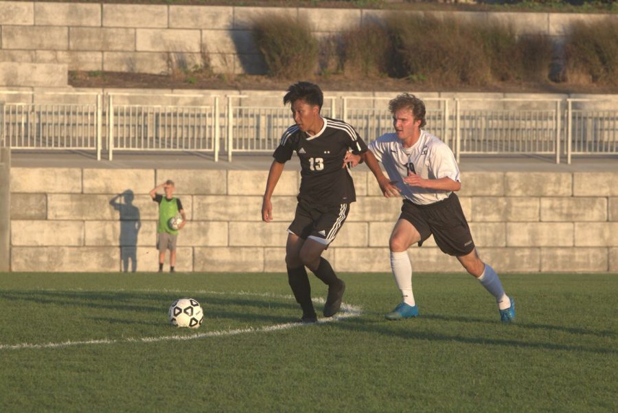 Junior Daniel Li dribbles away from Blue Valley West defender on Sept. 20 at the DAC. 
