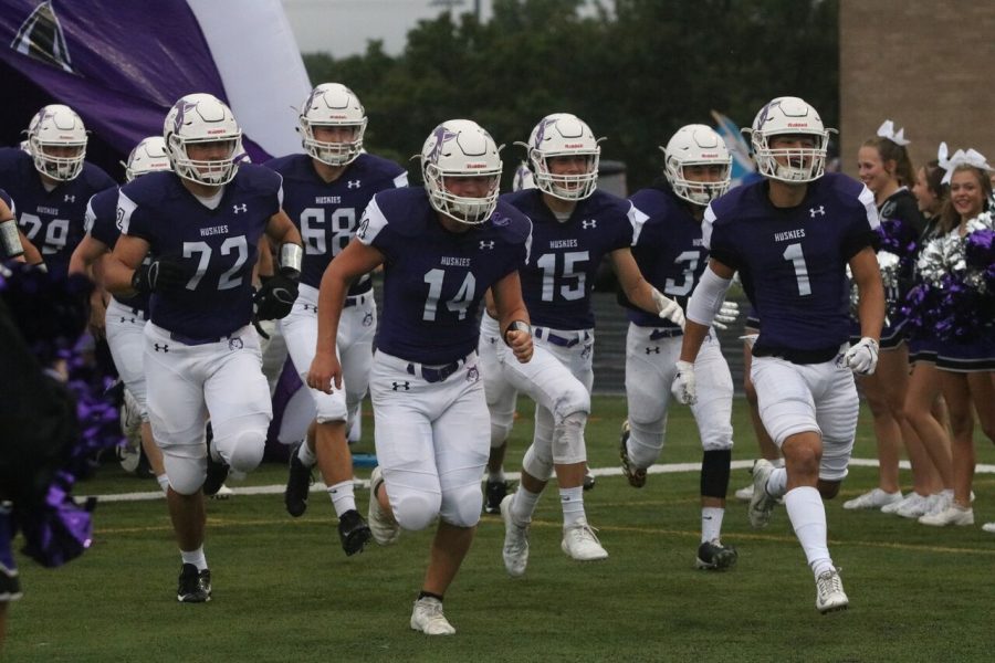 The Huskies run onto the field in the game against Harrisonville on Sept. 7 at the DAC. The Huskies were defeated by the Wildcats, 29-24. (Photo by Emily Farthing).