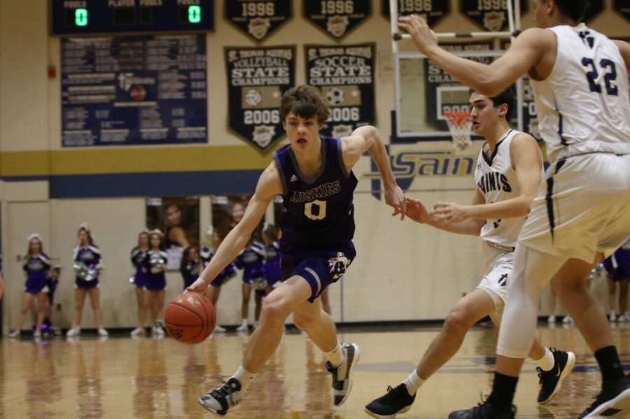 Senior+Christian+Braun+drives+the+ball+in+the+game+against+Saint+Thomas+Aquinas+on+Friday+Jan.+25+at+STA.+The+Huskies+defeated+the+Saints%2C+67-58.