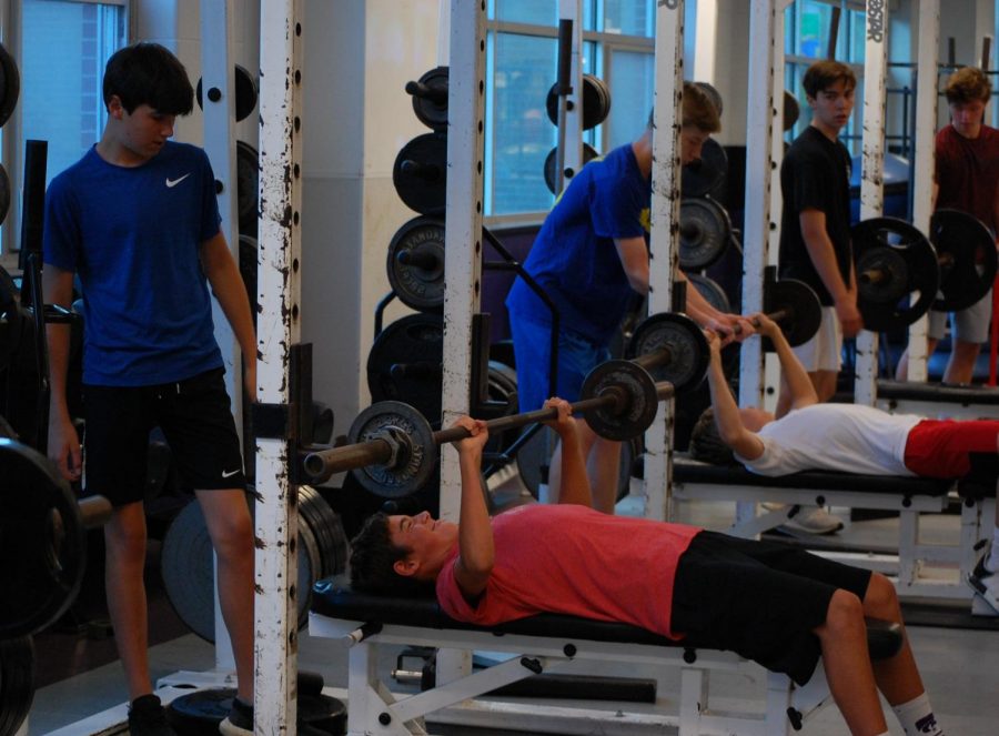Junior Nathan Monroe bench presses during summer workouts inside the weight room.  