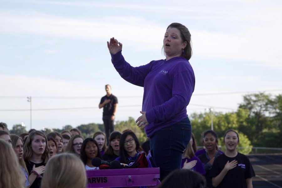 Choir director Beth Richey-Sullivan conducts the choir students during the National Anthem before the Husky Night parade in August of 2019. 