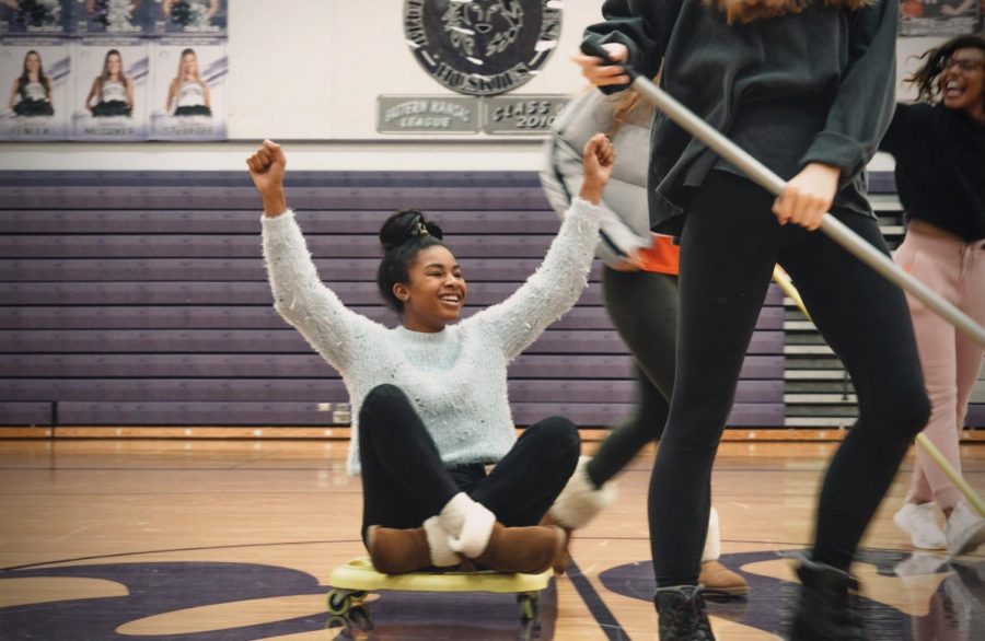 Senior Makenzie Iszard rides on a scooter while performing in the season spirit skit performance, Jan. 29
