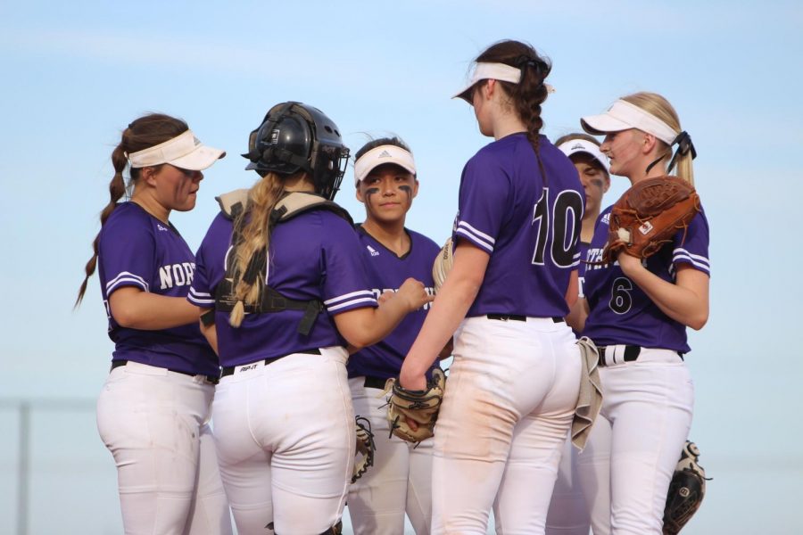 Huddled in a circle, the varsity softball team talks to each other during a game.