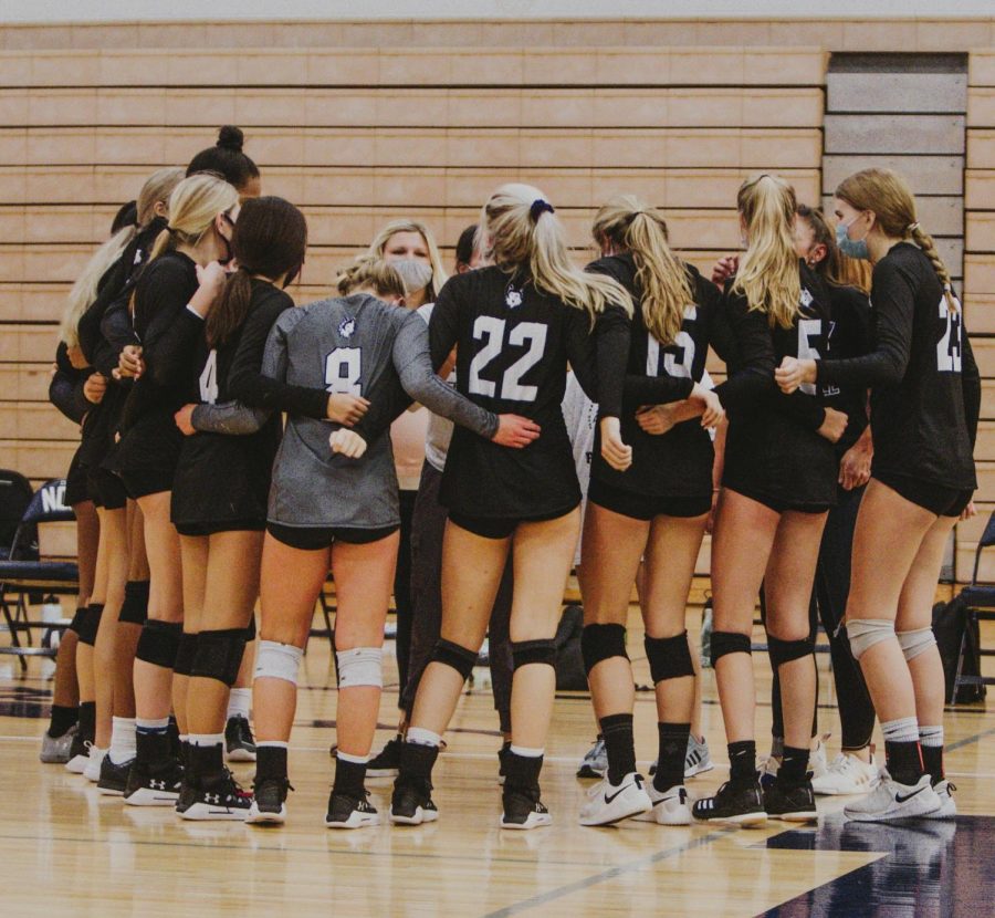 The Varsity volleyball team huddles together at the game against BVN.