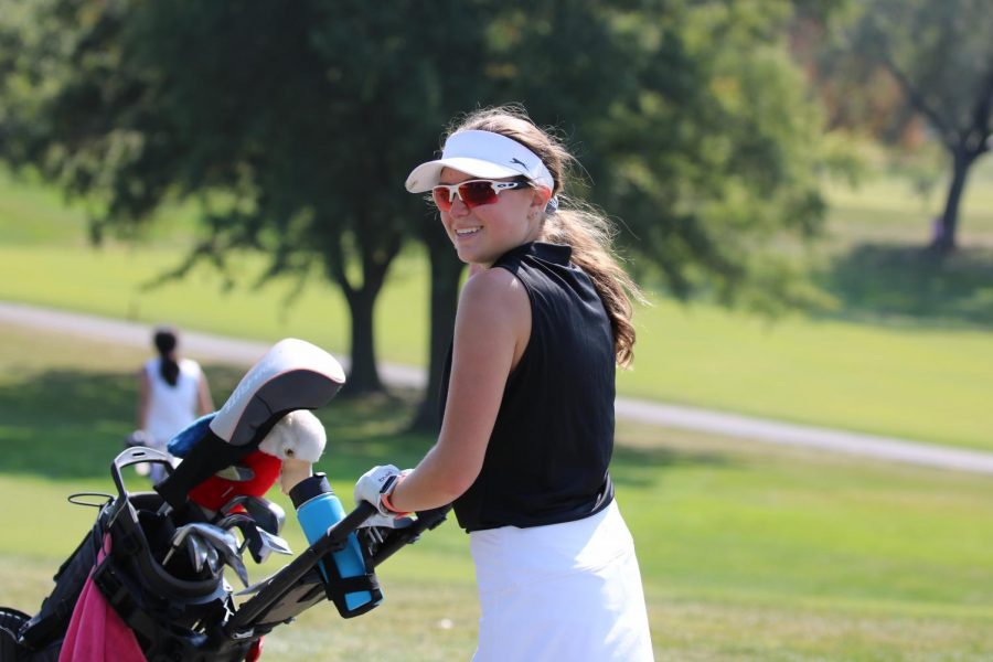 Senior Nicole Hiemenz pushes her bag during a golf practice.