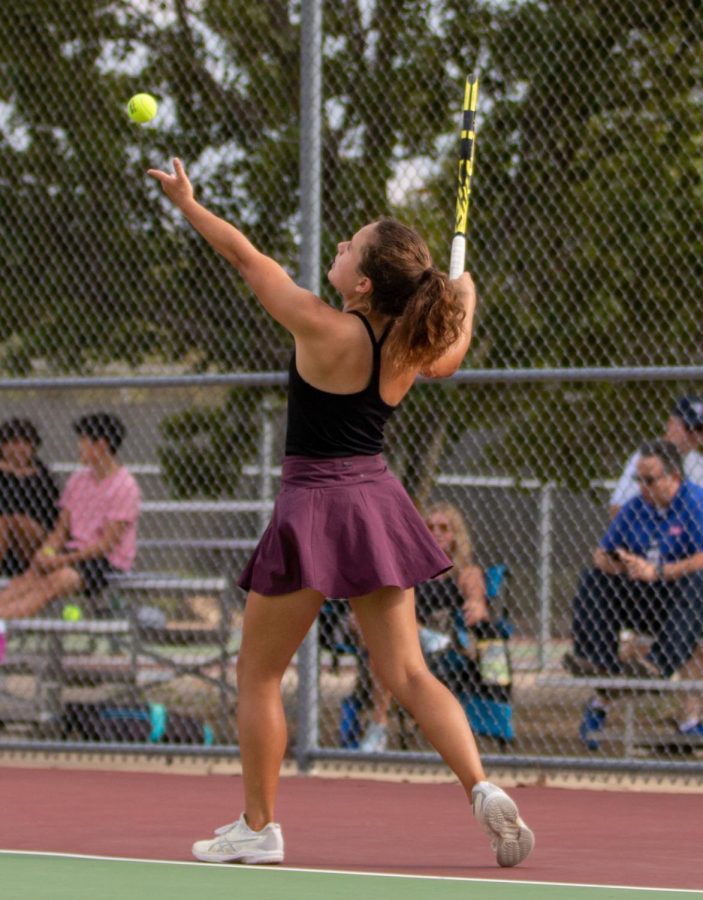 Senior Reagan King serves the ball in a tennis match against Blue Valley North on Sept. 20. (Photo by Norah Alasmar)