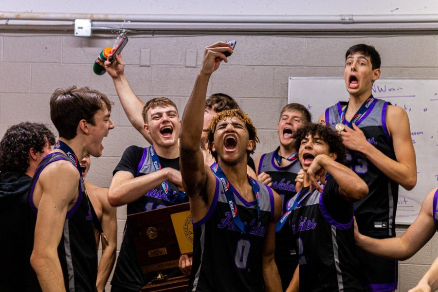 After defeating the Wichita Heights Falcons in the 2023 6A KSHSAA state championship, the boys basketball team celebrates in the locker room. 
