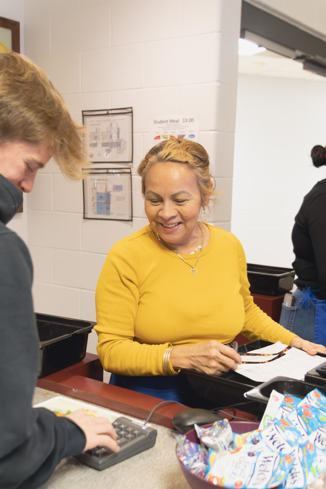 On Nov. 21, Maria Novelo laughs with a student while ringing them up for lunch.