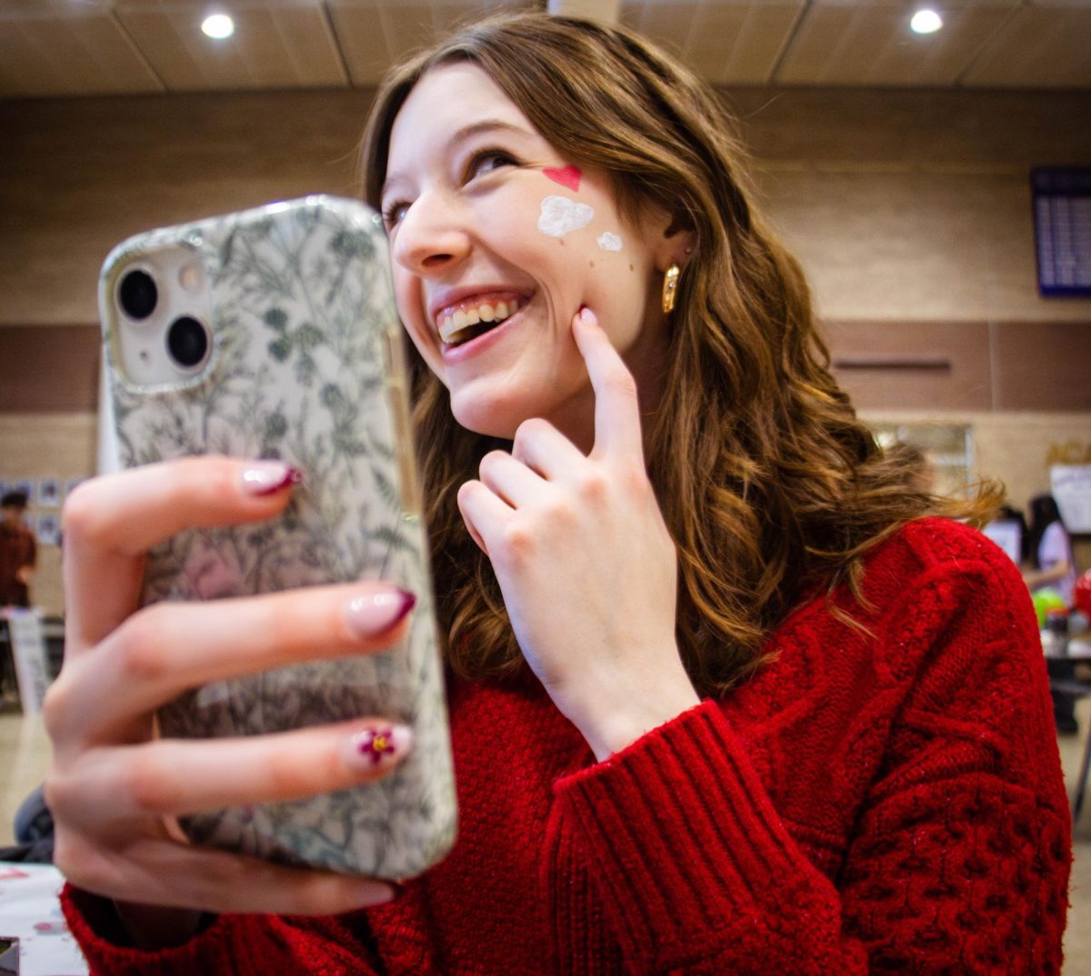 Senior Evie Fisher poses with her face painting done by the National Art Honor Society at the carnival Feb. 14.