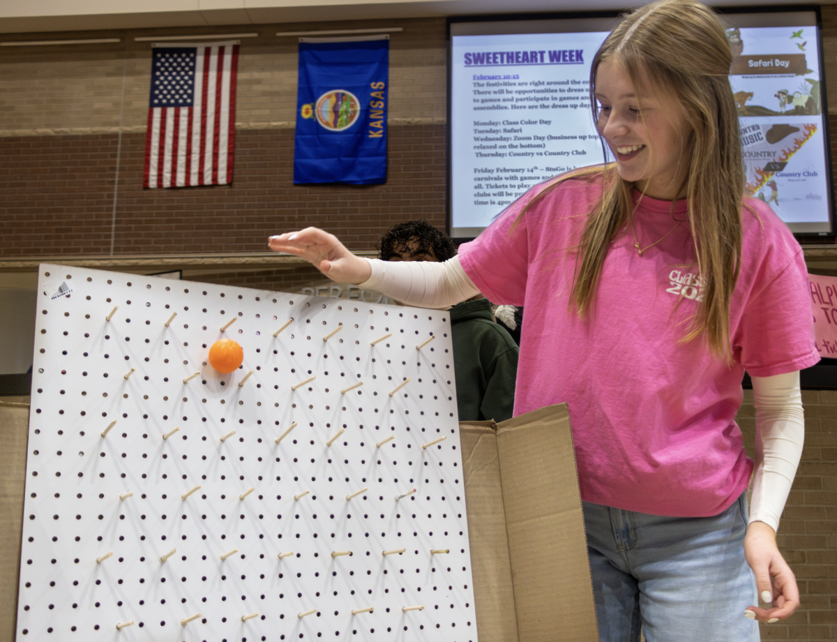 Sophomore Fiona Dudleston helps run the Pep Club booth at the Sweetheart Carnival Feb. 14. The addition of the carnival before the Sweetheart basketball game is one of the modifications made to this year's dance.