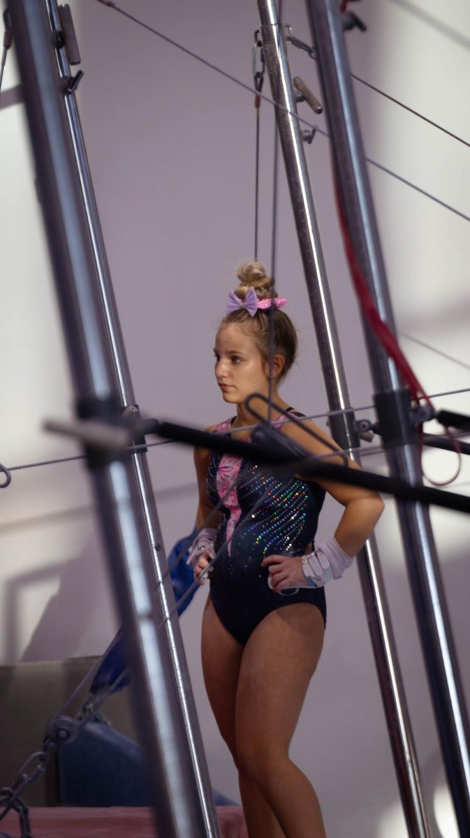 Among her other teammates, Brynnlee Zimmer listens to her coach as she directs the gymnasts on what to complete during practice. 