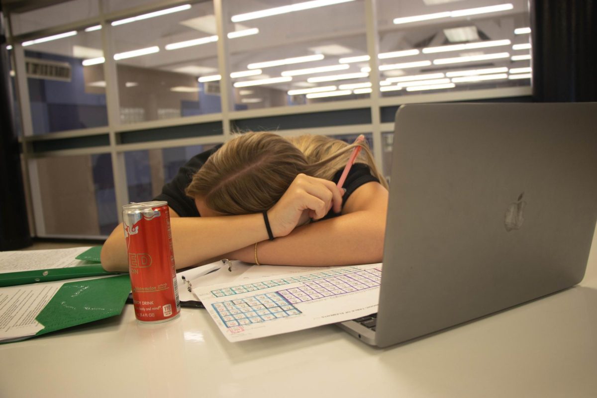 Sophomore Nadia Daney struggles to focus on her school work while running on five hours of sleep with an energy drink sitting beside her (Photo Illustration).
