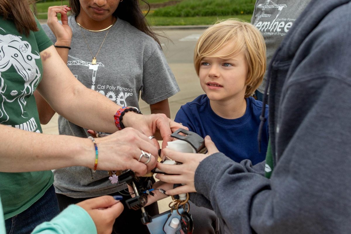 Femineers members and sponsor Karen Stohlmann adjust a prototype attached to Jon Silas Wiggins’ bike, April 25. Junior Isabella Large said they are creating an original design for Jon Silas, requiring them to experiment. “There was a lot of trial and error. We've gone through a couple of different 3D printing materials, as well as two different types of foam for the interior, and we have a bag with all of our failed prototypes in it. So it's mostly just seeing what prints well and what feels more comfortable,” Large said.